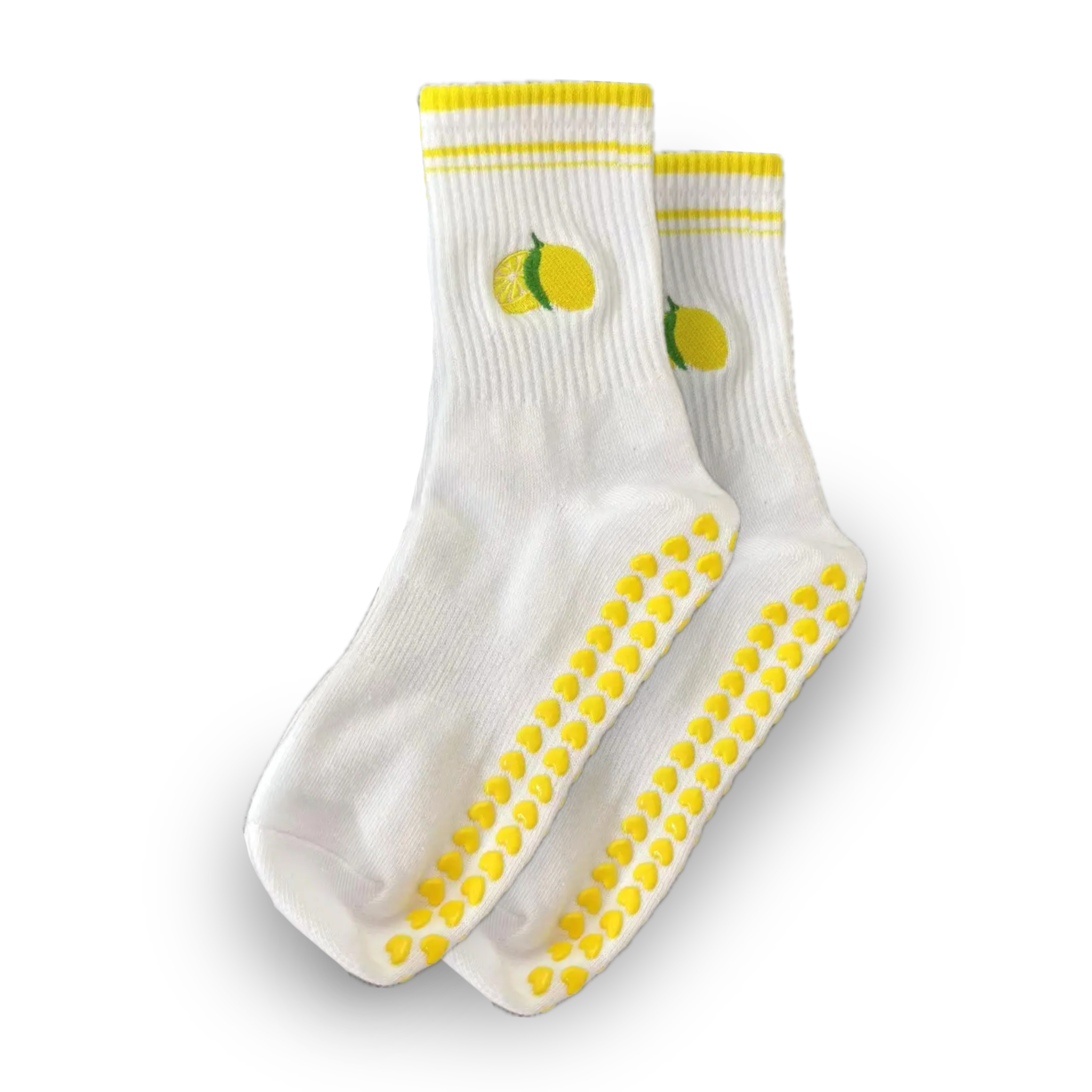 Pair of white crew grip socks with yellow stripe cuff trim, embroidered lemon and cut lemon slice near the ankle, and yellow heart-shaped non-slip grips on the soles, displayed on a solid black background, ideal for Pilates, yoga, barre, and fun everyday wear