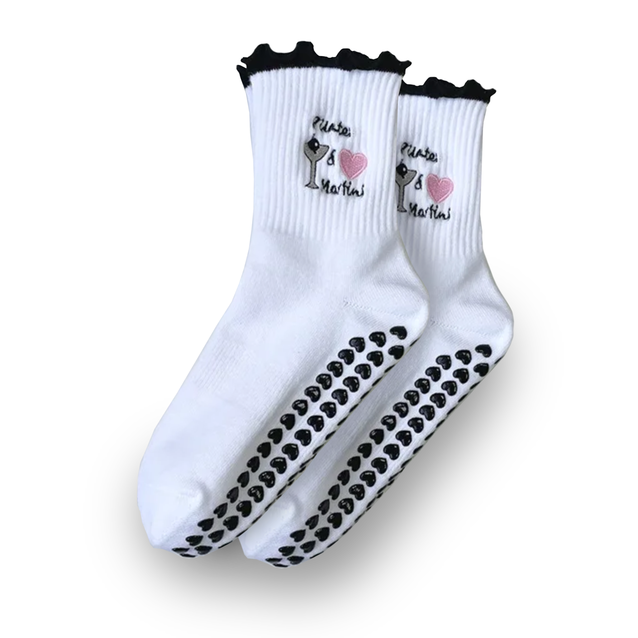 Pair of white crew grip socks with black ruffled cuffs, embroidered martini glass and pink heart with the text “Pilates & Martinis,” and black heart-shaped non-slip grips on the soles, displayed on a solid black background, ideal for Pilates, yoga, barre, and fun cocktail-themed workouts